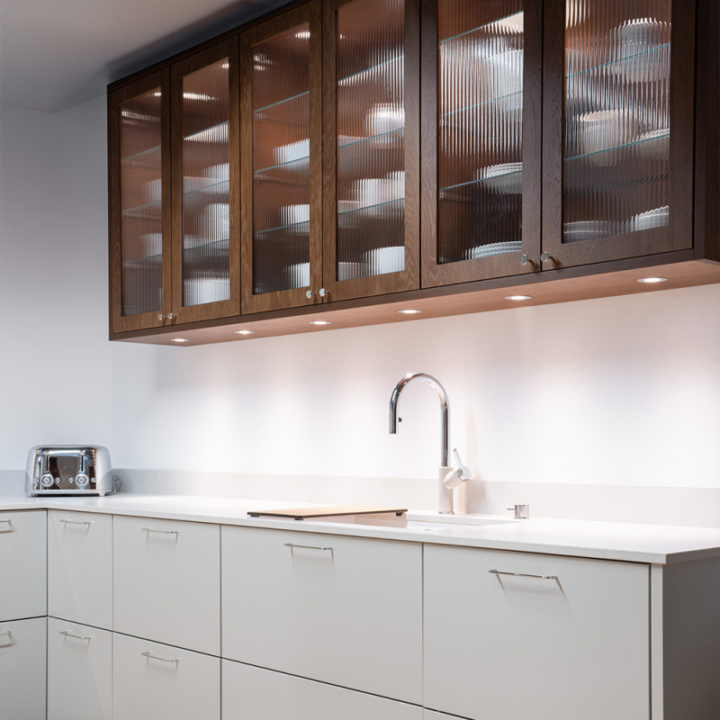 Kökshandtag Spira i vackert kök med överskåp i mörkbetsat trä och beiga köksluckor nedtill